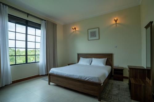 a bedroom with a bed and a large window at Bella Vista Villas Ltd in Mbarara