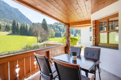 a balcony with a table and chairs and a large window at Jägers Highlineblick in Breitenwang