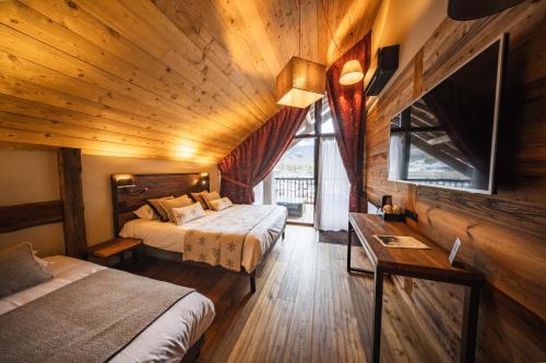 a bedroom with two beds and a wooden ceiling at Hôtel Neste de Jade in Saint-Lary-Soulan