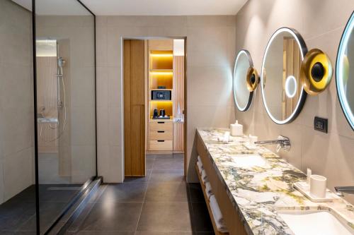 a bathroom with two sinks and two mirrors at Taghazout Bay Marriott Resort in Taghazout