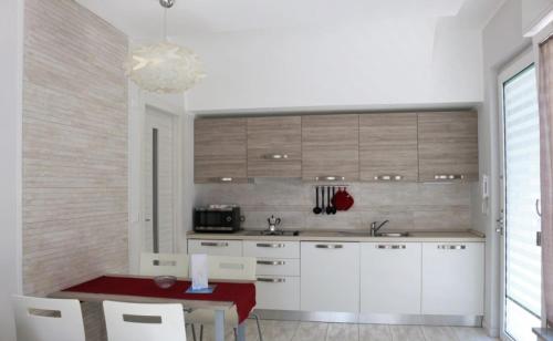 a kitchen with white cabinets and a red table and chairs at Nina Casa Vacanze in Finale Ligure