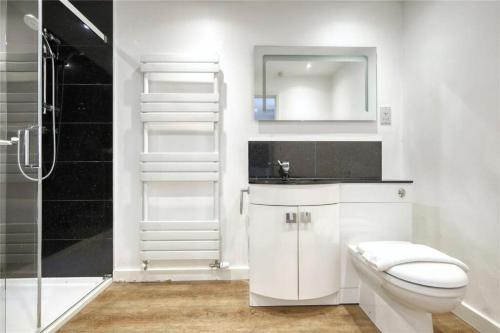 a white bathroom with a toilet and a shower at The Stables in Great Horkesley