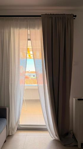 a window with curtains in a bedroom with a view of the ocean at Kazeta A-14,broj 28, Gajac in Skunca
