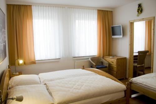 a bedroom with two beds and a desk and windows at Hotel zur Post Kleve in Kleve