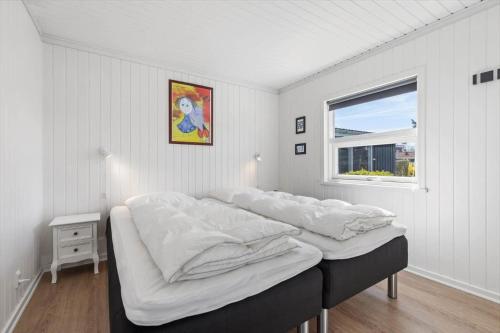 a bedroom with a bed with white sheets and a window at 8501-Grenaa-Ellevej-14 in Grenå Strand