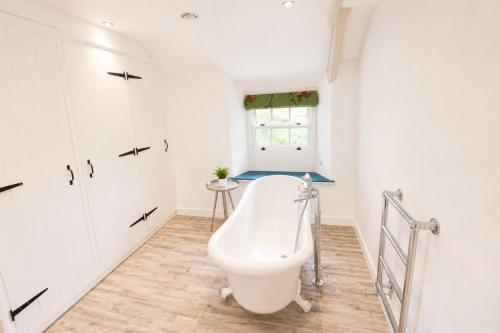 a bathroom with a bath tub in the corner at Red Squirrel Cottage, Hutton luxurious cottage in a rural setting 10 minutes to Ullswater 15 minutes to Keswick in Penruddock
