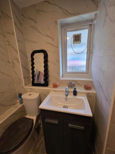 a bathroom with a sink and a toilet and a window at Olive & Ember - 1 Bed with private garden in Hythe
