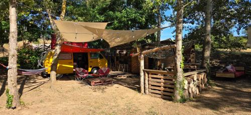 a rv with a tent and a fence and trees at van domloc in Carcassonne