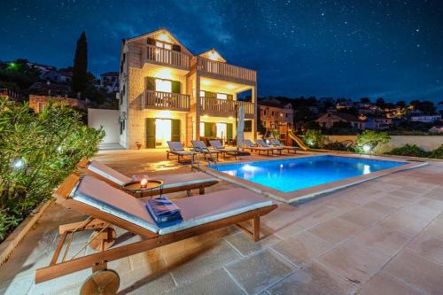 a villa with a swimming pool at night at Villa Janie - Modern Pool Apartments Splitska in Splitska