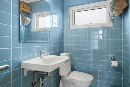 a blue tiled bathroom with a toilet and a sink at 1671-Vejby-Blommevaenget-2 in Vejby