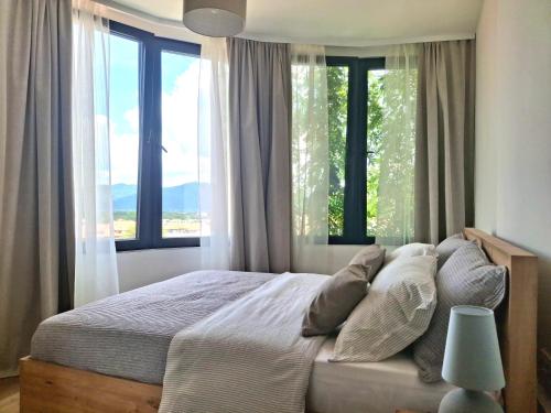 a bedroom with a large bed with large windows at Horizont 360 Gold in Vrnjačka Banja
