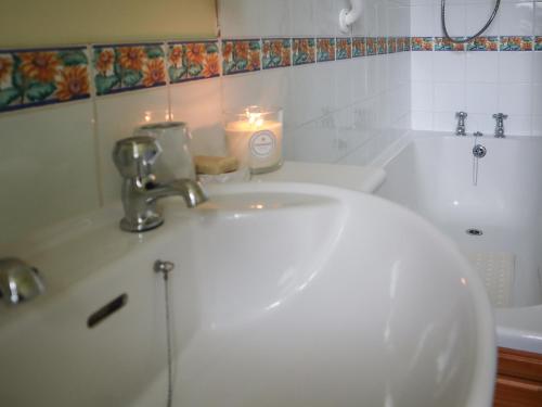 a bathroom with a white sink and a candle at Elizabeth Lodge - Cottage in Alford
