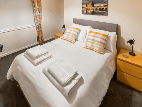 a bed with white towels stacked on top of it at Elizabeth Lodge - Cottage in Alford