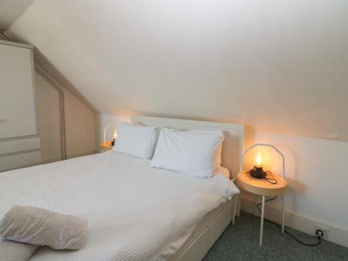 a bedroom with a white bed with a side table at Footdee Cottage in Aberdeen