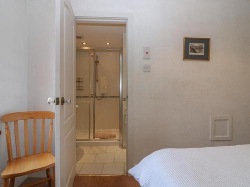 a bedroom with a shower and a bed and a chair at Footdee Cottage in Aberdeen