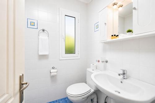 a white bathroom with a toilet and a sink at Villa Penelope Sea View in Argostoli