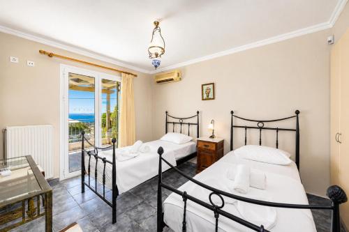two beds in a room with a view of the ocean at Villa Penelope Sea View in Argostoli