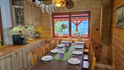 a dining room with a long table in a kitchen at Szyszka & Igiełka in Rycerka Górna