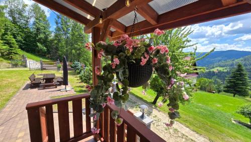 a porch with flowers on it with a view at Szyszka & Igiełka in Rycerka Górna