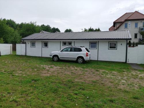 a white car parked in front of a house at Radosna Zatoka - DOMKI Z OGRODZENIEM in Międzywodzie