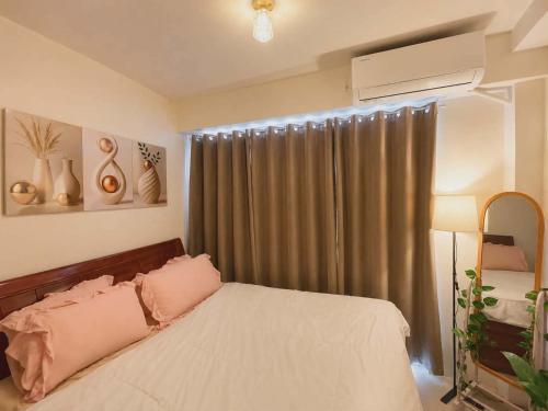 a bedroom with a bed with pink pillows and a window at Shore 1 tower D Pasay City in Manila
