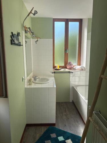 a bathroom with a sink and a tub and a window at Au fil de Lods in Lods