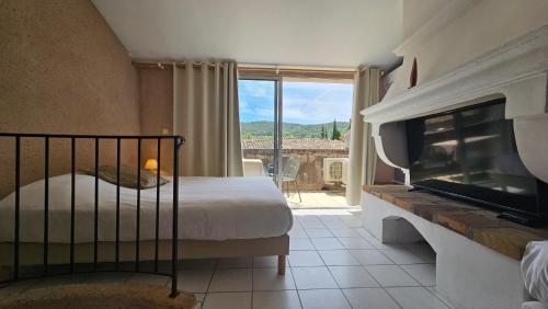 a bedroom with a bed and a fireplace and a tv at Hôtel la Fête en Provence in Vaison-la-Romaine