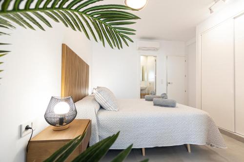 a bedroom with a bed with a lamp and a plant at NerjaPlus Terraza de Ladera Apartamento V11 in Nerja
