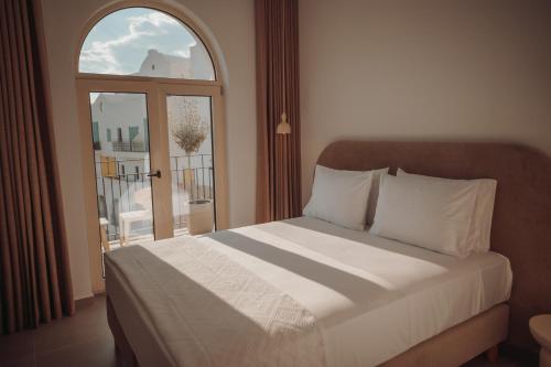 a bedroom with a bed and a window with a balcony at IONEO Dhermi in Dhërmi