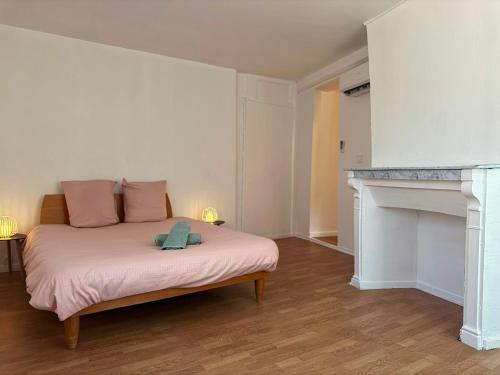 a bedroom with a bed with pink sheets and a fireplace at Maison SYD saint-Junien in Saint-Junien