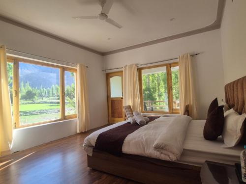 a bedroom with a large bed and large windows at Hunder Nature Retreat in Hundar