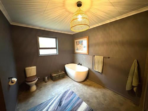 a bathroom with a tub and a toilet and a sink at Raven in Stormsrivier