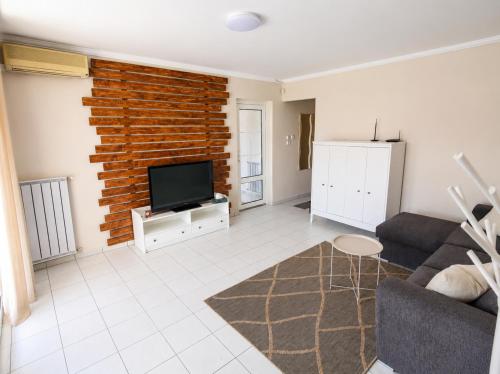 a living room with a brick wall and a flat screen tv at Csendes Panoráma Apartman in Balatonalmádi