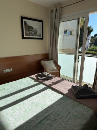 a bedroom with a bed and a chair and a window at Villa Ferrera Select A in Cala Ferrera