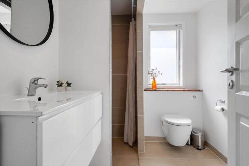 a white bathroom with a toilet and a sink at 30392-Odder-Delfinvej-5 in Odder