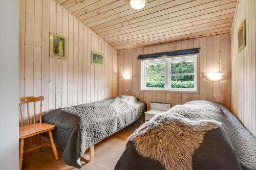two beds in a room with wooden walls and a window at C11645-Hemmet-Kosigvaenget-100 in Hemmet