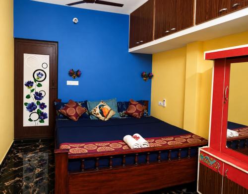 a bed in a room with a blue wall at La Baie Homestay in Pondicherry
