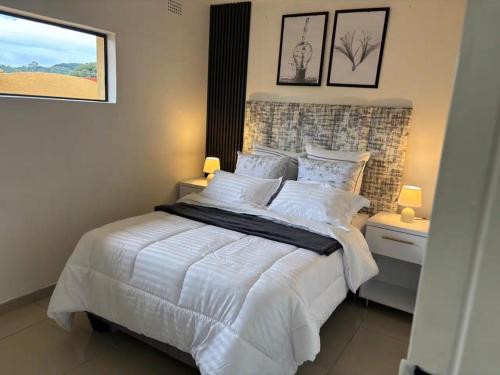 a bedroom with a bed with white sheets and a window at Monti's Villa Suites in Southgate