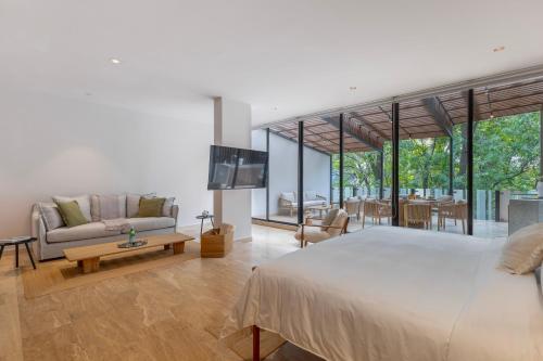 a bedroom with a large bed and a living room at Capitalia Temistocles Polanco in Mexico City