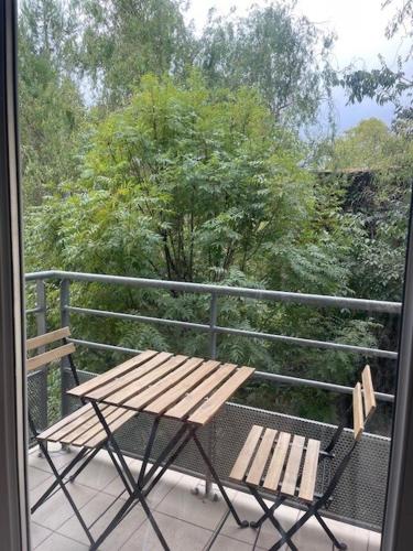a balcony with a wooden table and two benches at Studio Résidence les Jardins du Musée in Alès
