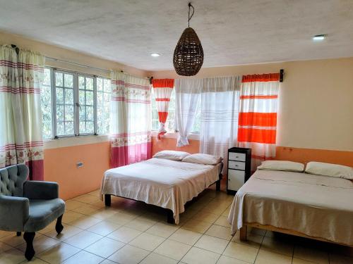 a bedroom with two beds and a chair and windows at EL Jardin De Los Anturios in Xico