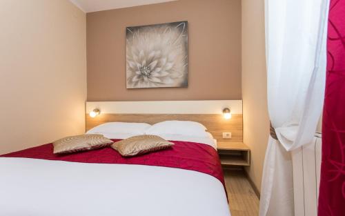 a bedroom with a white bed with red sheets and pillows at Apartments Polonijo in Baška