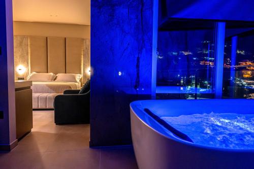 a bathroom with a tub in a room with a bedroom at Nuna Hotel & Apartments in Vlorë