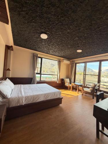 a bedroom with a bed and a desk and windows at Bön Valley in Jomsom