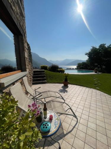 a patio with a table with a bottle and flowers at Casa Ronco Frati, piscina vista lago in Pisogne