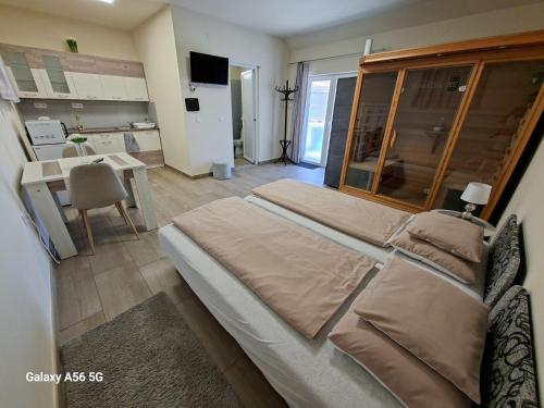 a bedroom with a large bed and a kitchen at Tölgyfa Vendégház in Kiskőrös
