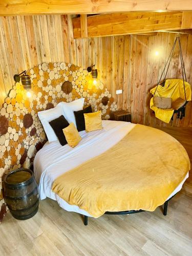 a bedroom with a large bed in a room with wooden walls at La Cabane Tonneau - Les Pieds dans le Pré in Les Landes-Génusson