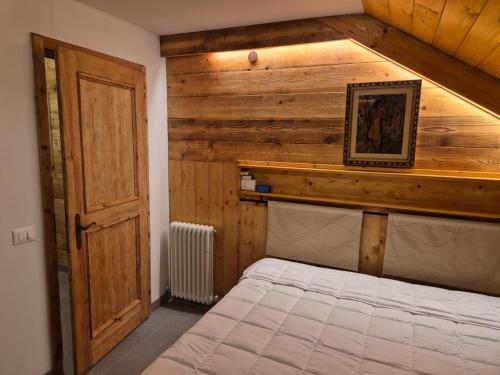 a bedroom with a bed with a wooden wall at Mansarda al Lago Casa Lavaredo in Auronzo di Cadore