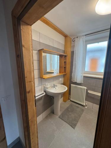a bathroom with a sink and a mirror and a window at Mansarda al Lago Casa Lavaredo in Auronzo di Cadore