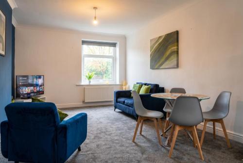 a living room with a blue couch and a table and chairs at St John's Flats, Newsome in Huddersfield